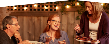 Banner photo at the bottom of the page showing a man hosting a backyard barbecue and sitting down to dinner with friends and family.  
