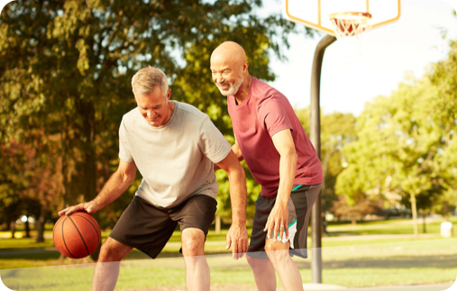 Photo of 2 men playing one-on-one basketball on an outdoor court. 