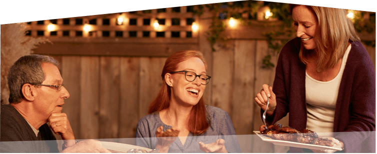 Banner photo at the bottom of the page showing a man hosting a backyard barbecue, sitting down to dinner amid friendly conversation.