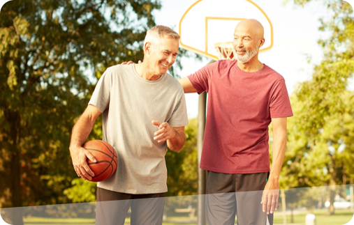 Photo of aPhoto of two men, one giving the other a pat on the back as they take a break from one-on-one basketball on an outdoor court.  man looking affectionately at his dog as they walk together down a park path on a beautiful fall day.